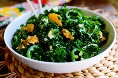 a white bowl filled with green vegetables on top of a wicker tablecloth covered place mat