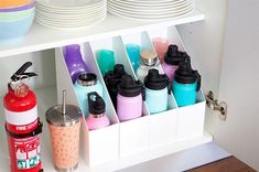 the kitchen cabinet is organized with cups, plates, and other condiments on it