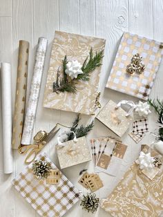 christmas wrapping supplies laid out on a white wooden surface with pine cones and evergreen branches