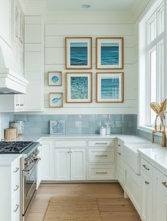 a kitchen with white cabinets and pictures on the wall above the stove, along with an area rug