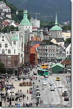 a city street filled with lots of traffic next to tall buildings and green roofed roofs