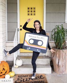 a woman holding up a sign that says halloween dj mix on the front porch with her feet in the air