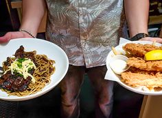 two people holding plates with food on them