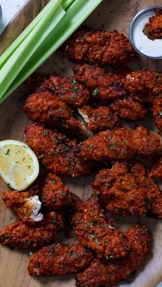 some chicken wings and celery on a wooden platter next to dipping sauces