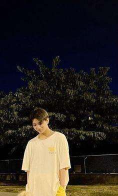 a young man standing on top of a field next to a yellow frisbee