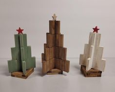 three pieces of art made out of wood with red stars on top and green ones in the middle