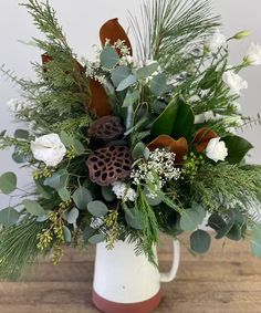 a white vase filled with flowers and greenery