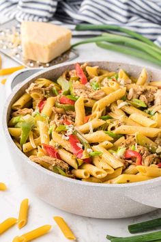 a pan filled with pasta and meat on top of a table next to green onions