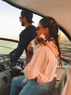 a man and woman riding on top of a boat with a dog in their lap