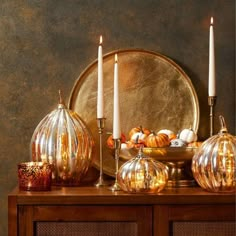 a table topped with candles and pumpkins on top of a wooden dresser next to a mirror