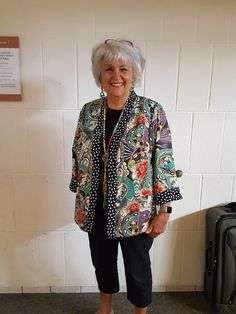 an older woman standing in front of a wall