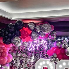 balloons and streamers are hanging from the ceiling in front of a wall with congratulations written on it