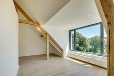 an empty room with large windows and wooden beams