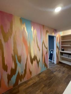 an empty room with painted walls and wooden flooring in the foreground is a bookshelf