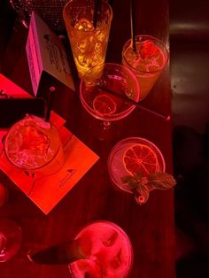 several glasses filled with drinks on top of a wooden table