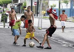 several young men playing soccer on the street