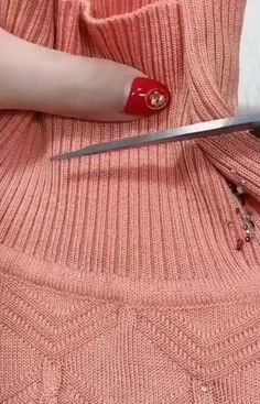 a woman is cutting up a pink sweater with scissors