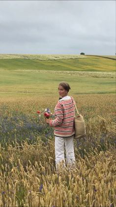 a woman standing in a field holding flowers