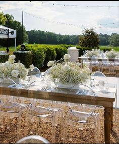 a table with clear chairs and white flowers in vases sitting on top of it