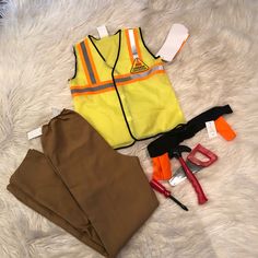 an assortment of construction related items laid out on a white furnishing area with scissors, pliers and safety vests