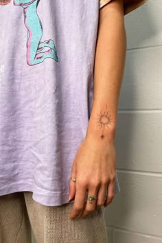 a person with a small tattoo on their left arm and the sun behind her head