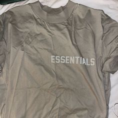 New Never Worn Essentials T-Shirt Sand Color Oversized Spring Streetwear Drop Shoulder Tops, Oversized Logo Print Tops For Summer, Essential Crew Neck Top With Logo Print, Essential Logo Print Crew Neck Top, Essential Graphic Print Tops For Streetwear, Spring Oversized Tops With Logo Print, Casual Drop Shoulder Tops With Letter Print, Casual Drop Shoulder Top With Text Print, Urban Gray Tops For Spring