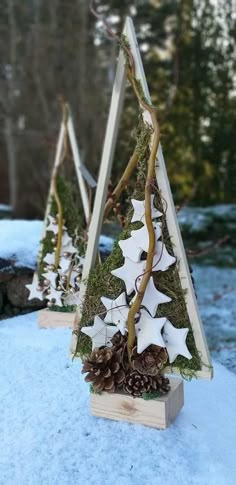 three christmas trees made out of wood and pine cones are sitting on snow covered ground