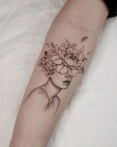 a woman's arm with a flower tattoo on her left forearm and the head of a girl