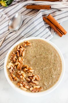 a white bowl filled with oatmeal and nuts on top of a table