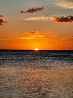 the sun is setting over the ocean with clouds in the sky and water below it