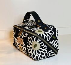 a black and white flowered bag sitting on top of a table next to a wall