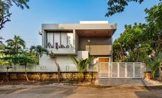 a house that is in the middle of some trees and dirt area with a fence around it