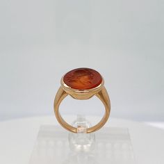 A fine Etruscan Revival gold & carnelian signet ring.  With a bezel-set cabochon carnelian that has an intaglio carved image of an Ancient Greek or Roman scholar or philosopher.  The carnelian is oval shaped and set in a wide-banded, unmarked 18K setting.  Simply a wonderful, substantial ring!  Date: Late 19th or Early 20th Century  Overall Condition: It is in overall good, as-pictured, used estate condition.  Condition Details: There is some minor loss to the edge of the bezel setting and some Antique Carnelian Intaglio Rings, Formal Carnelian Signet Ring With Polished Finish, Classic Carnelian Signet Ring For Formal Events, Classic Carnelian Signet Ring For Formal Occasions, Formal Orange Cabochon Ring, Formal Carnelian Oval Cabochon Jewelry, Formal Carnelian Oval Signet Ring, Formal Oval Carnelian Signet Ring, Classic Carnelian Signet Ring For Anniversary