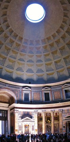 people are standing in the middle of a room with a circular ceiling light above it