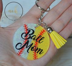 a hand holding a baseball keychain with the word bae mom on it