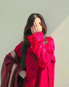 a woman covering her face while standing against a wall