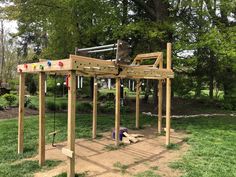 a wooden play structure in the middle of a park