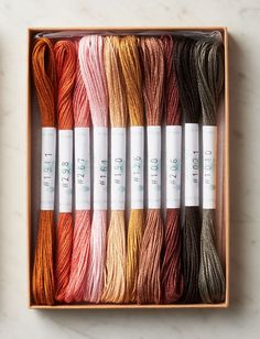 six skeins of multicolored thread in a wooden box