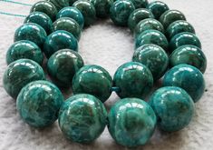 a bunch of green marble beads on a white surface with some string in the background