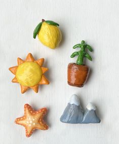 four small plastic toys are arranged in the shape of plants and mountains, including a lemon