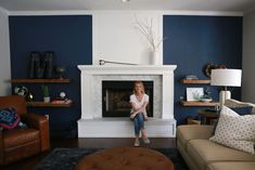 a woman sitting on a couch in front of a fireplace with blue and white walls