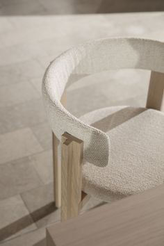 a wooden chair with a white fabric seat cover on top of it and a tile floor in the background