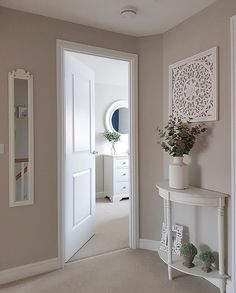 a hallway with a white table and mirror on the wall, potted plant next to it