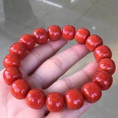 a hand holding a red beaded bracelet