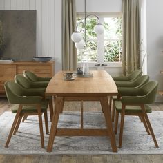 a dining room table with green chairs and a white rug on the floor in front of it