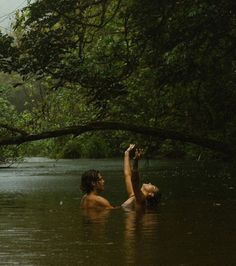 two people are in the water and one is reaching up