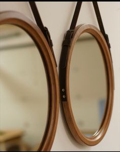 two round mirrors mounted to the side of a wall