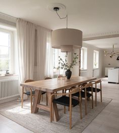 a dining room table with chairs and a lamp in the corner, next to a large window