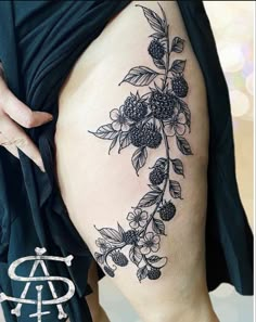 a woman's thigh with flowers and leaves tattoo on her leg, showing the lower part