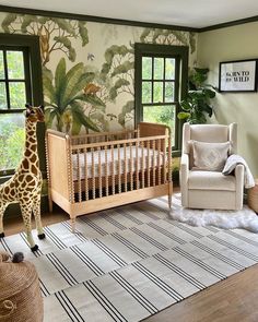 a giraffe standing next to a baby crib in a room filled with furniture